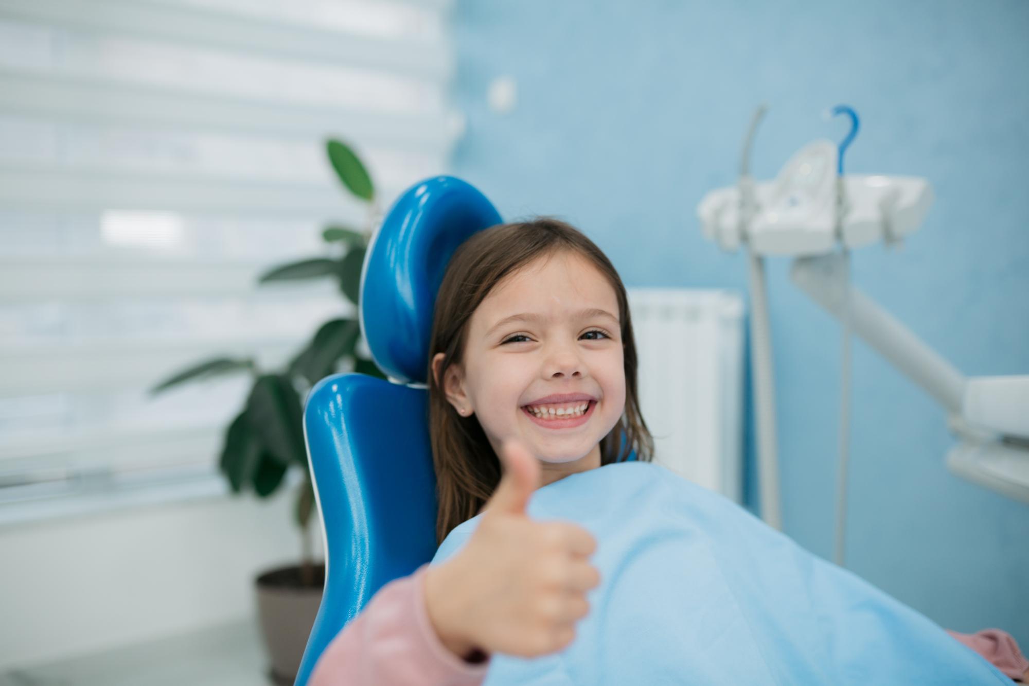 GettyImages-1440613172-caucasian little girl in dental chair smiling thumbs up (5) lincoln braces